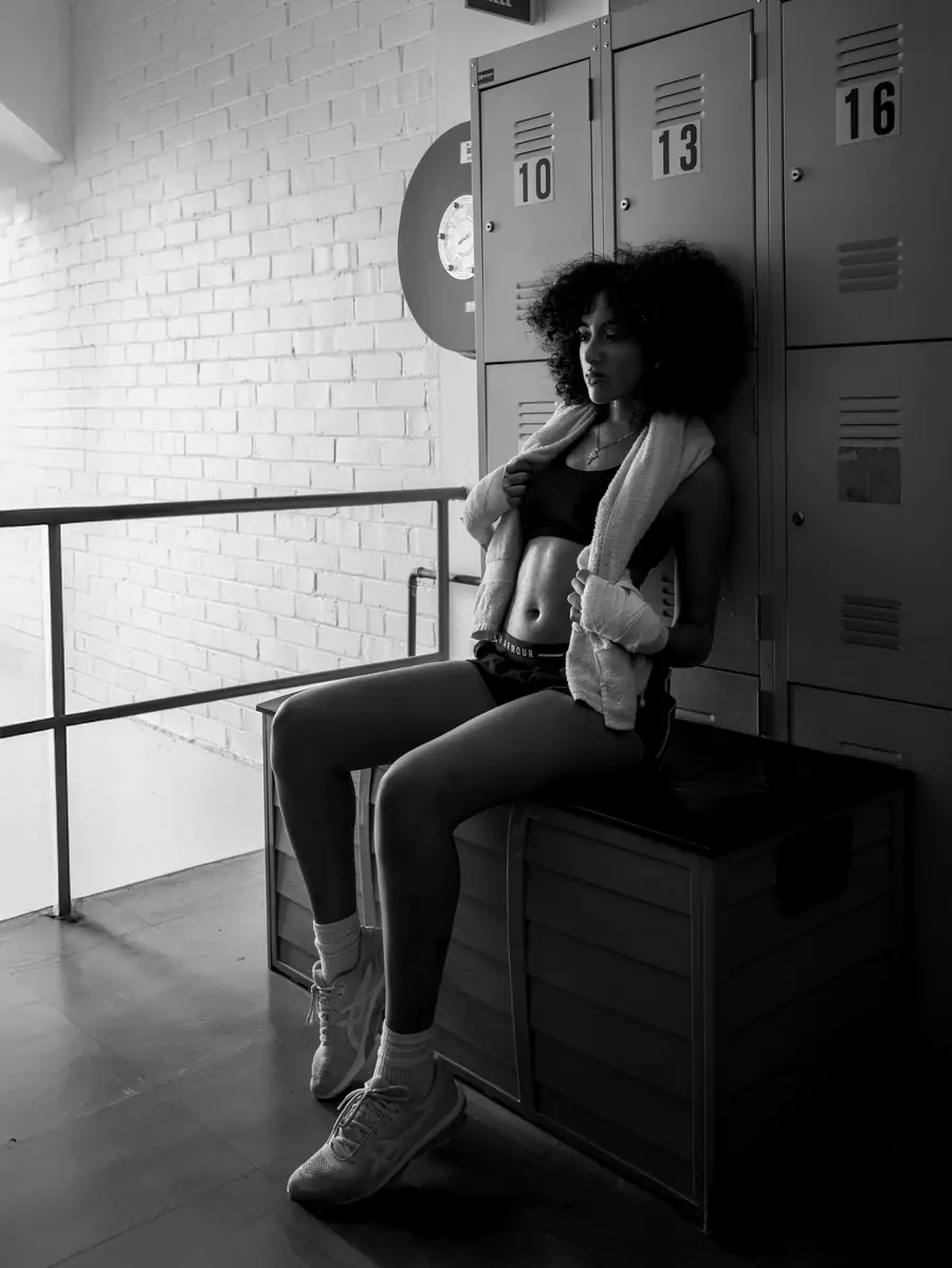 Sportive assise dans les vestiaires après sa séance, serviette sur les épaules.